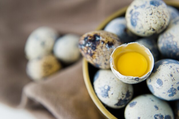 Ovos de codorna em uma tigela de ouro, um ovo quebrado.