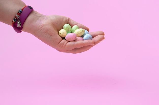 Foto ovos de codorniz coloridos naturais em uma mão feminina em um fundo rosa banner close up