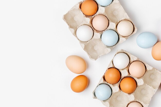 Ovos de cor natural marrom e branco em caixa de ovo. Composições em cores pastel. Conceito de Páscoa. Camada plana, vista superior