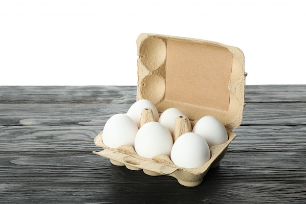 Foto ovos de galinha branca em caixa na mesa de madeira, isolada no branco