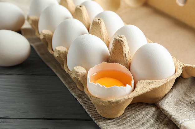 Ovos de galinha branca em caixa na mesa de madeira