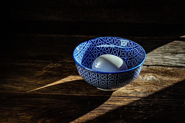 Ovos de galinha branca em um prato de cerâmica azul sobre uma mesa de madeira de cozinha.