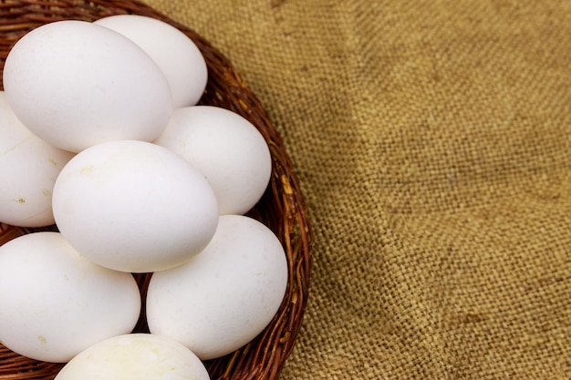 Ovos de galinha branca na cesta de vime em fundo de saco