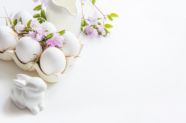 Ovos de galinha branca orgânica com flores da primavera em branco. Páscoa.