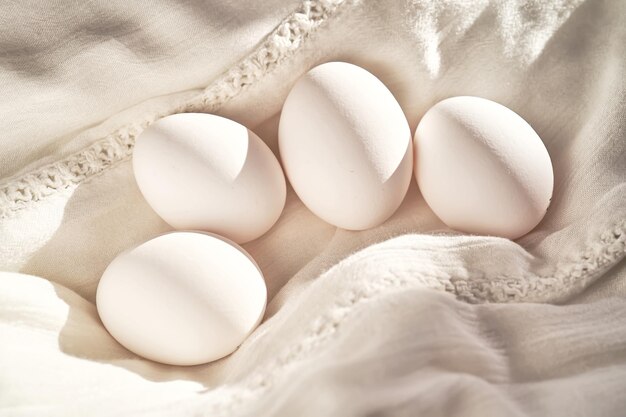 Ovos de galinha brancos em uma toalha de linho branca em close-up