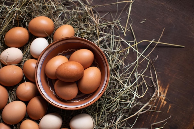 Ovos de galinha caseiros em uma tigela e no feno Conceito de comida natural
