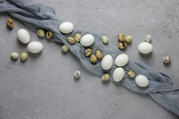 Foto ovos de galinha e codorna brancos com gaze cinza sobre um fundo cinza de concreto