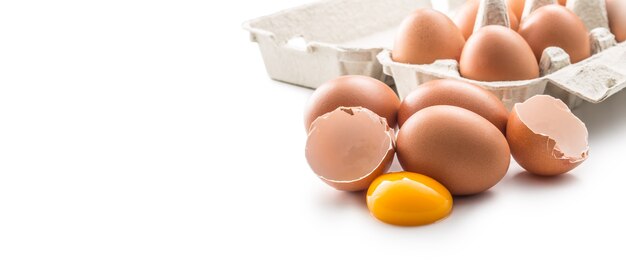 Ovos de galinha e ovo quebrado com gema isolada no fundo branco.