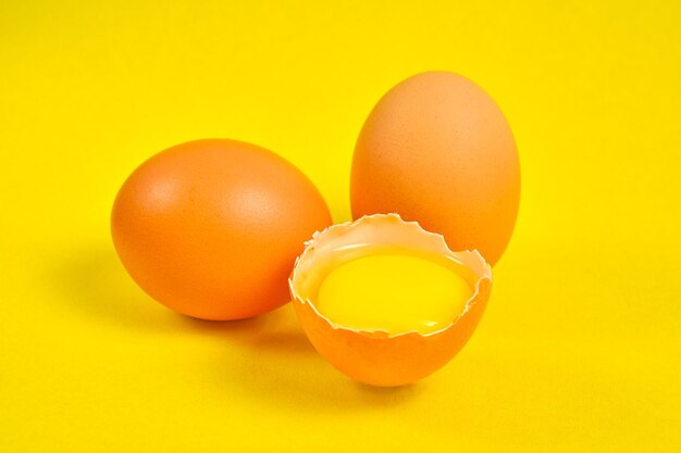 Ovos de galinha em um fundo amarelo quebrado com gema.