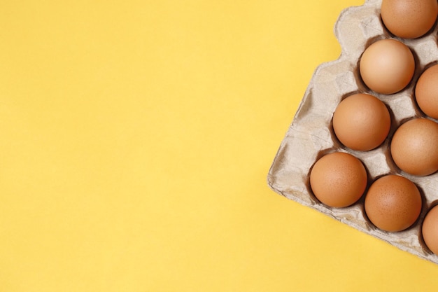 Ovos de galinha em uma caixa de papelão pronta para cozinhar em um fundo amarelo