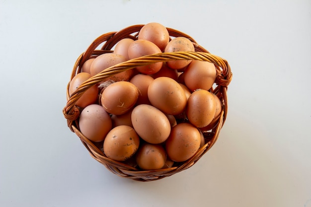 Ovos de galinha em uma cesta de vime em um fundo branco.
