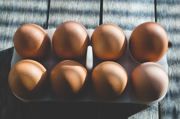 Ovos de galinha em uma mesa velha de madeira no início do sol as sombras das persianas caem sobre o fundo e os ovos