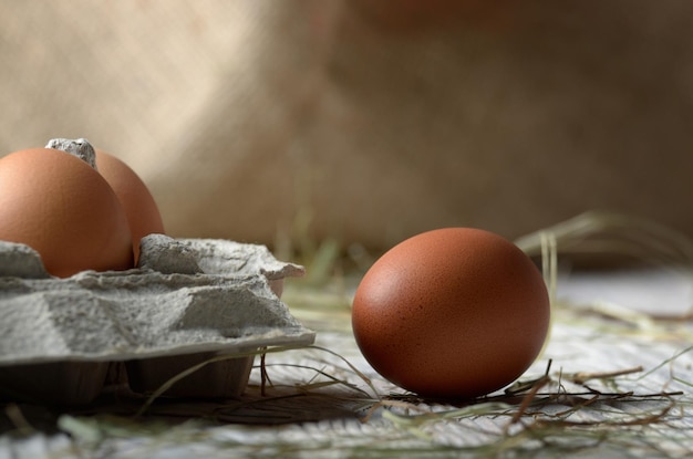 Ovos de galinha marrons orgânicos crus em caixa de papel ecologicamente correta na mesa de madeira de cozinha branca