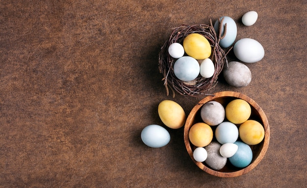 Foto ovos de páscoa amarelo cinza azulados em um ninho e um prato