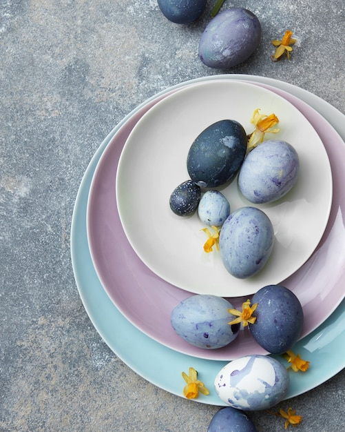 Ovos de Páscoa azuis em um prato colorido com flores em um fundo de pedra