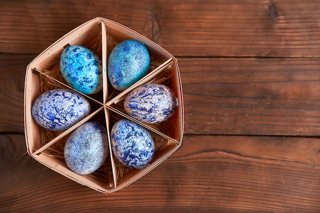 Ovos de Páscoa azul na cesta na mesa de madeira