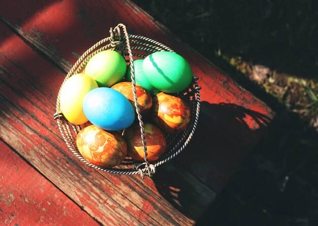 Ovos de páscoa coloridos brilhantes em uma cesta nas tábuas de madeira