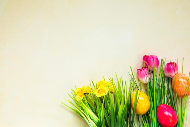 Ovos de páscoa coloridos com flores e ovos de páscoa de grama verde desaparecem em fundo amarelo claro e