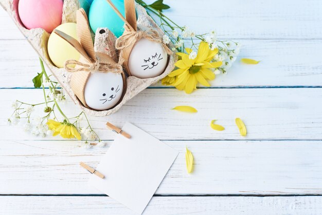 Ovos de Páscoa coloridos com rostos pintados na bandeja de papel com decoração em um fundo branco