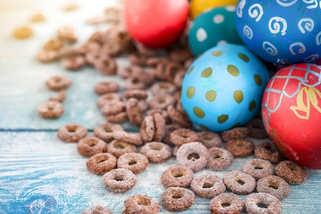 Ovos de páscoa coloridos e anéis de milho doce em fundo de madeira feliz páscoa