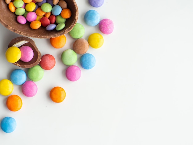 Ovos de páscoa coloridos e de chocolate com drageia doce em fundo branco