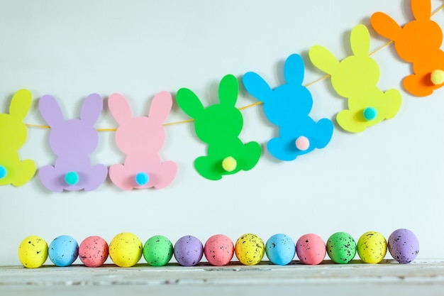 Ovos de Páscoa coloridos e festão da Páscoa coelhinho feito à mão em fundo bege. Conceito de feliz Páscoa.