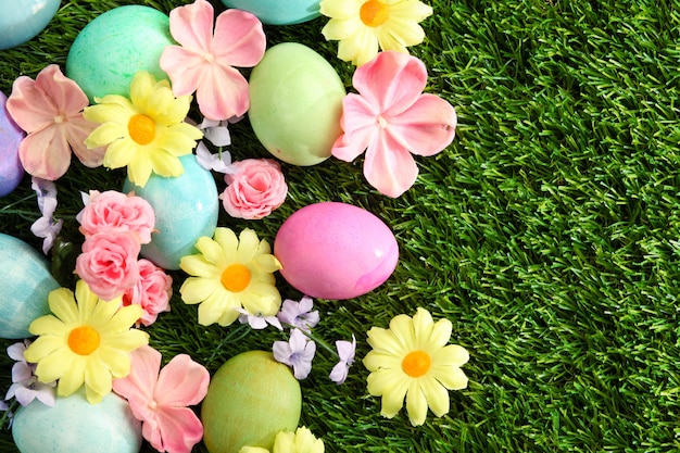 Ovos de páscoa coloridos na grama com fundo de flores