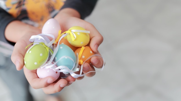 Ovos de páscoa coloridos nas mãos da criança, foco suave e cores em tons.