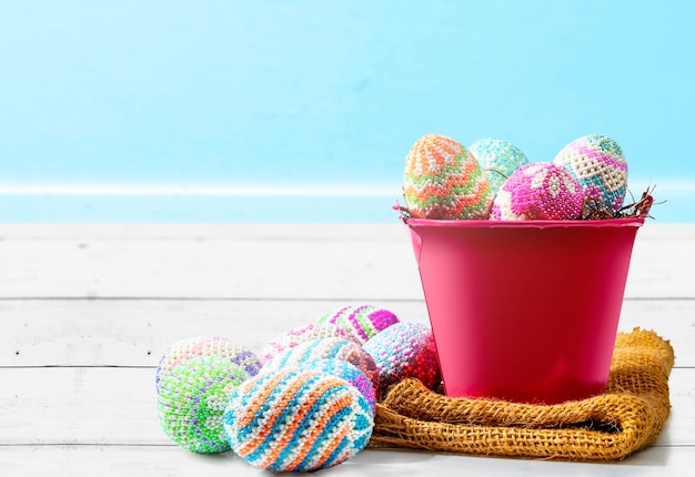 Ovos de Páscoa coloridos no ninho em um balde vermelho com tecido em cima da mesa. Feliz Páscoa