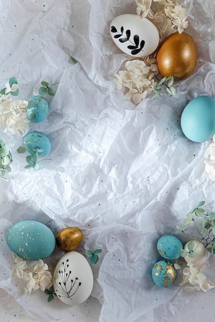 Ovos de páscoa com doces e flores com espaço de cópia em papel branco cartão de feliz páscoa ovos azuis e dourados brancos em papel de embrulho