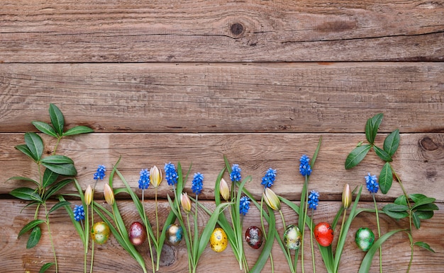 Ovos de Páscoa com flores da primavera em uma mesa de madeira