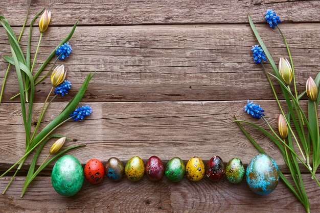 Ovos de Páscoa com flores da primavera em uma mesa de madeira