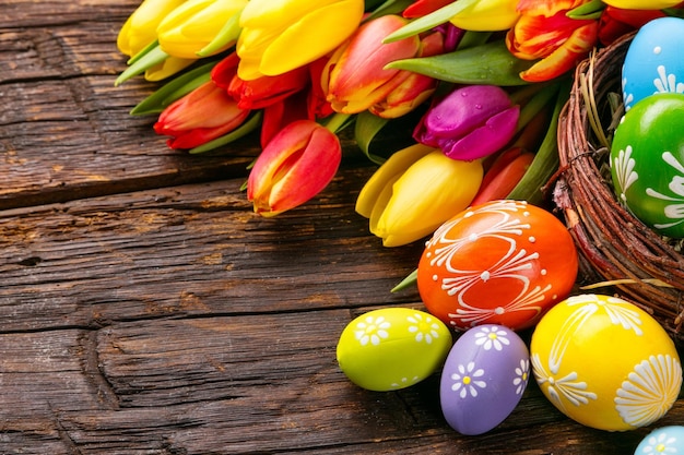 Ovos de Páscoa com tulipas em tábua de madeira