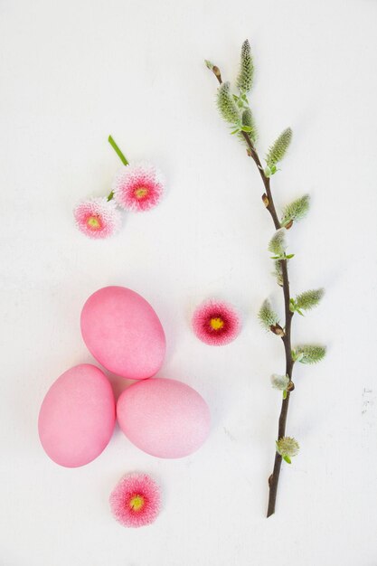 Ovos de Páscoa cor-de-rosa tingidos à mão com decoração de margarida e amentilho em fundo de madeira