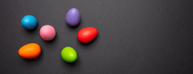 Ovos de Páscoa cores pastel pintados no banner de fundo cinza escuro