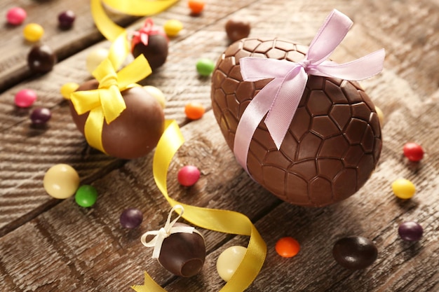 Foto ovos de páscoa de chocolate com laços de fita colorida em fundo de madeira