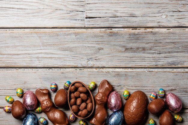 Ovos de páscoa de chocolate e coelhinhos em um fundo de madeira rústico