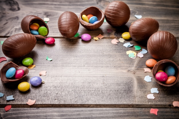 Ovos de Páscoa de chocolate e doces em fundo de madeira