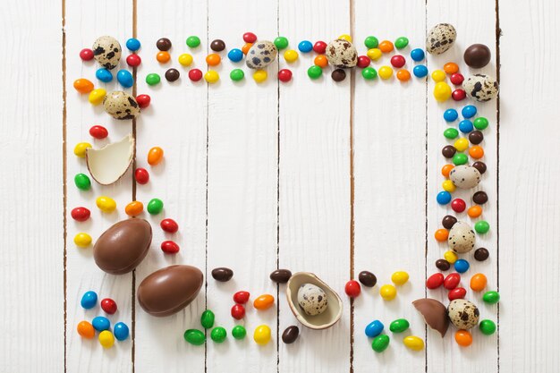 Ovos de Páscoa de chocolate e doces em superfície de madeira branca