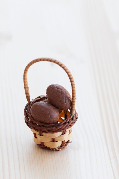 Ovos de páscoa de chocolate em uma cesta em uma mesa de madeira