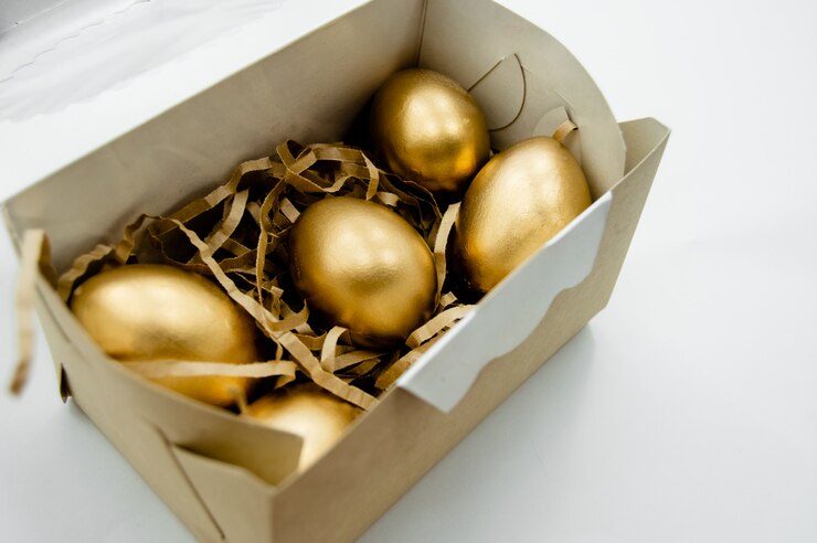Ovos de Páscoa de ouro em uma caixa com estrelas douradas sobre fundo branco