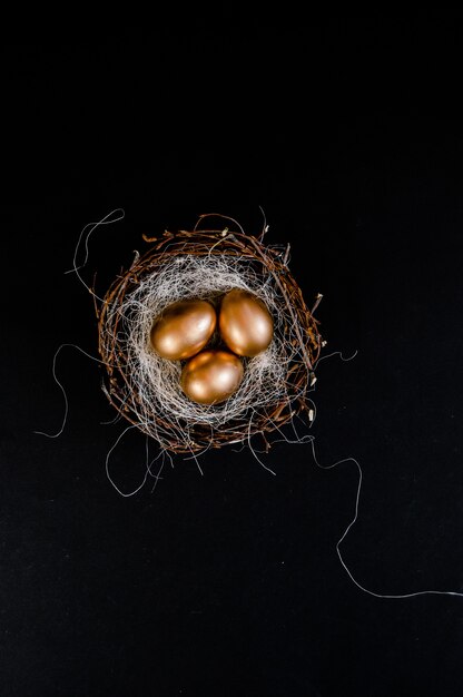 Ovos de Páscoa de ouro no ninho de pássaros em fundo preto
