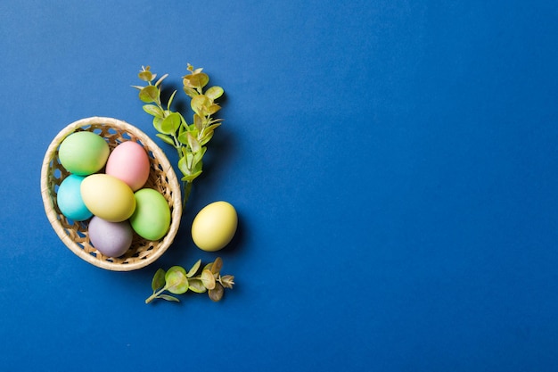 Ovos de páscoa de várias cores na cesta tecida em fundo colorido Conceito de férias de ovos de páscoa de cor pastel com espaço de cópia