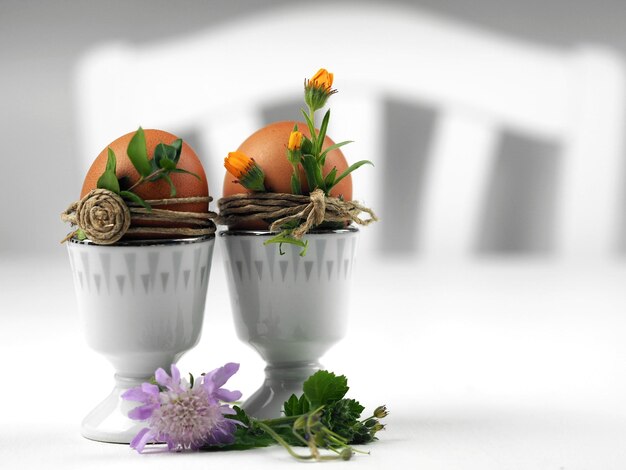 Ovos de Páscoa decorados com flores naturais em copos de ovo estilo Cottage
