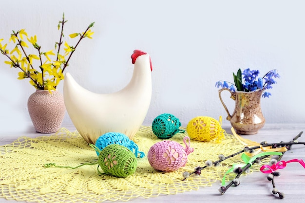 Ovos de Páscoa decorados contra o fundo de uma figura de galinha e buquês