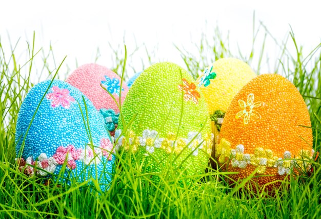 Ovos de páscoa decorados na grama no fundo branco