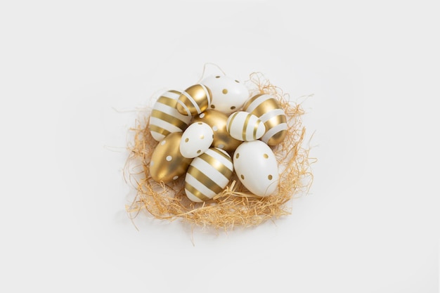 Ovos de páscoa decorativos e palha em um fundo branco