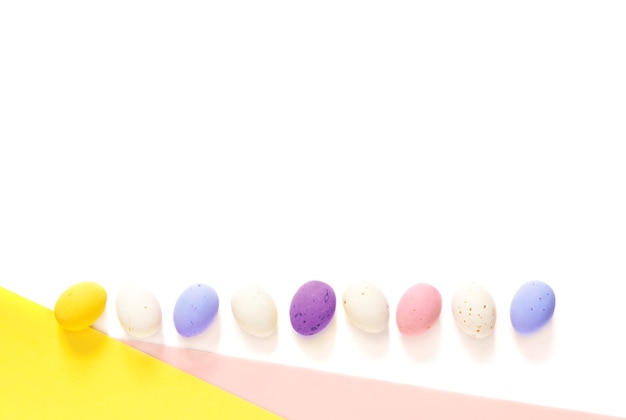 ovos de Páscoa doces em um fundo rosa e amarelo branco claro. Feliz páscoa plana leiga. copie o espaço