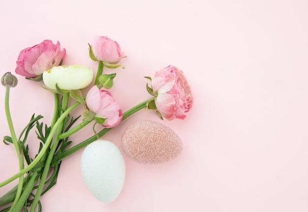 Ovos de Páscoa e buquê de flores de botões de ouro no espaço de cópia de fundo rosa pastel