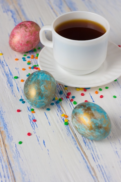 Ovos de páscoa e café, doces coloridos de decoração em cima da mesa de madeira. conceito de páscoa